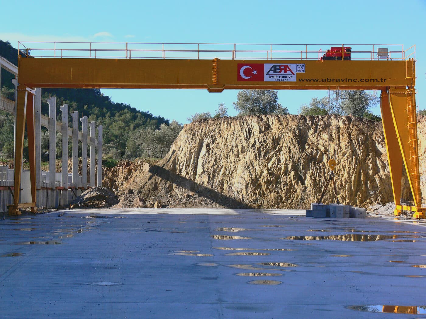 ABRA gantry crane spanning an open precast yard beside a rock face